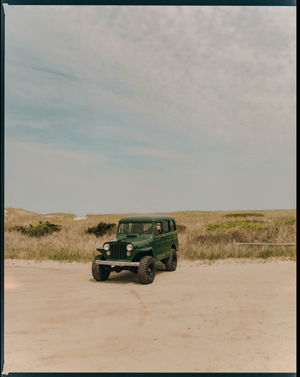 A vintage green jeep parked on the sand dunes in Wellfleet