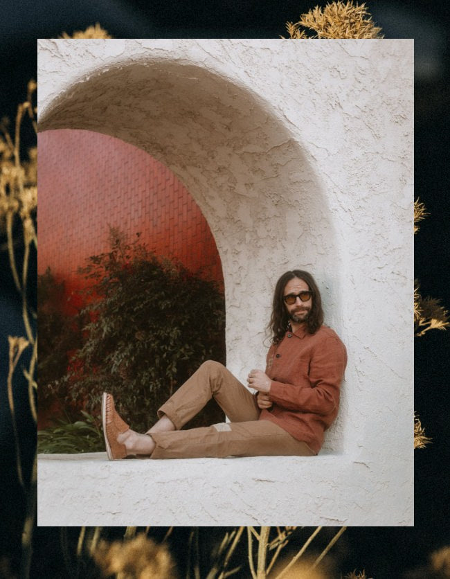 Daren sitting beneath a white arched wall in The Embroidered Ojai