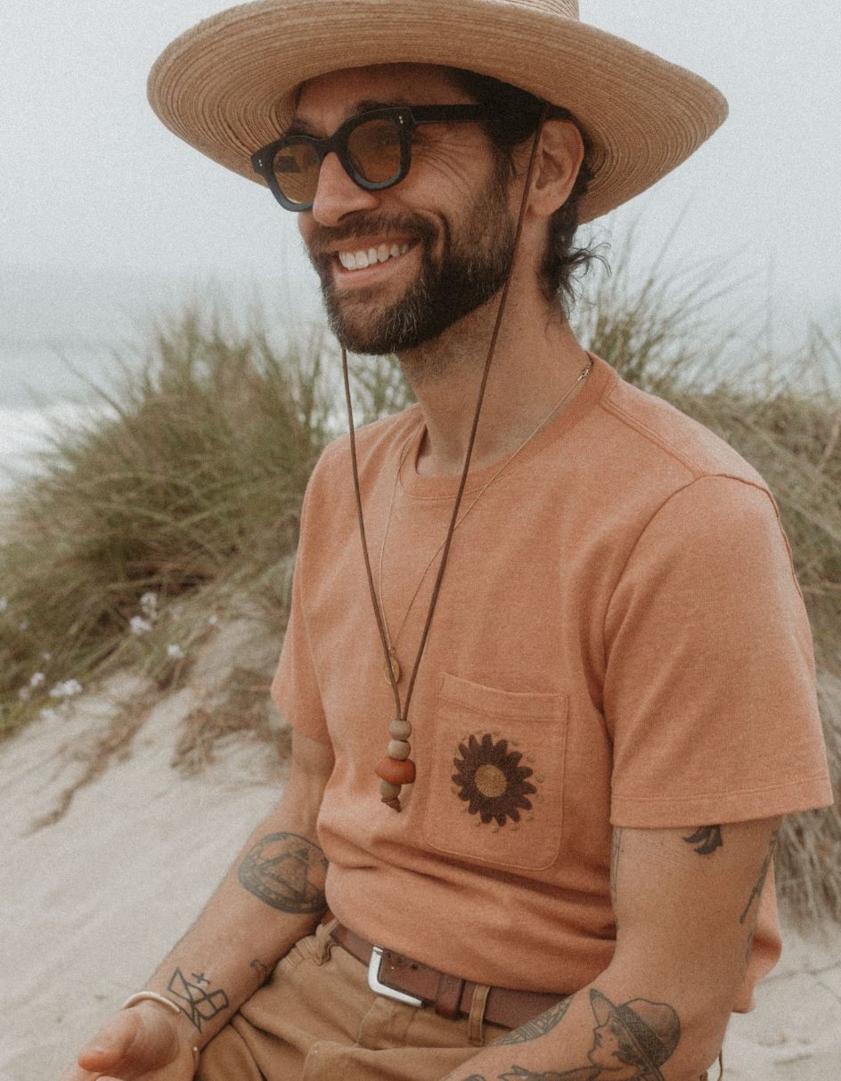 Daren smiling on the beach in The Embroidered Heavy bag Tee