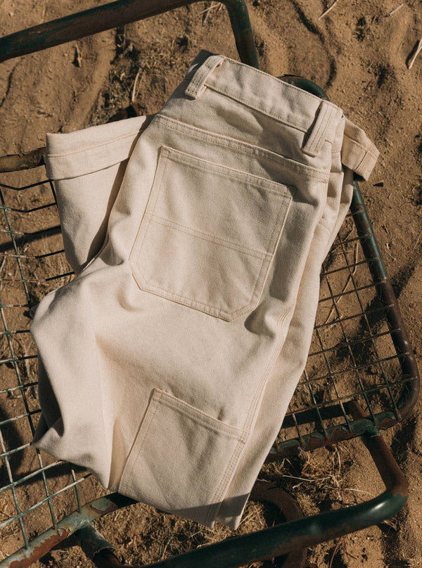 The Painter Pant in Seeded Natural Chipped Canvas, folded on a metal chair