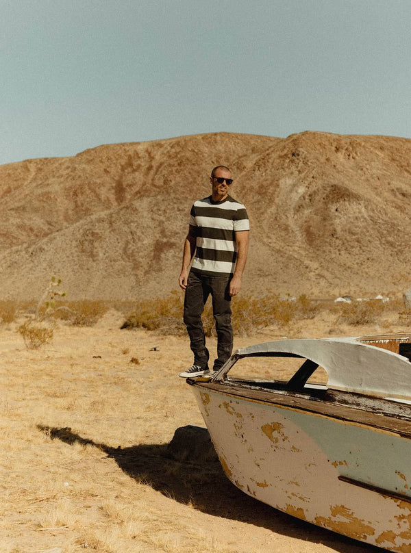 Model standing on a vintage boat in the desert
