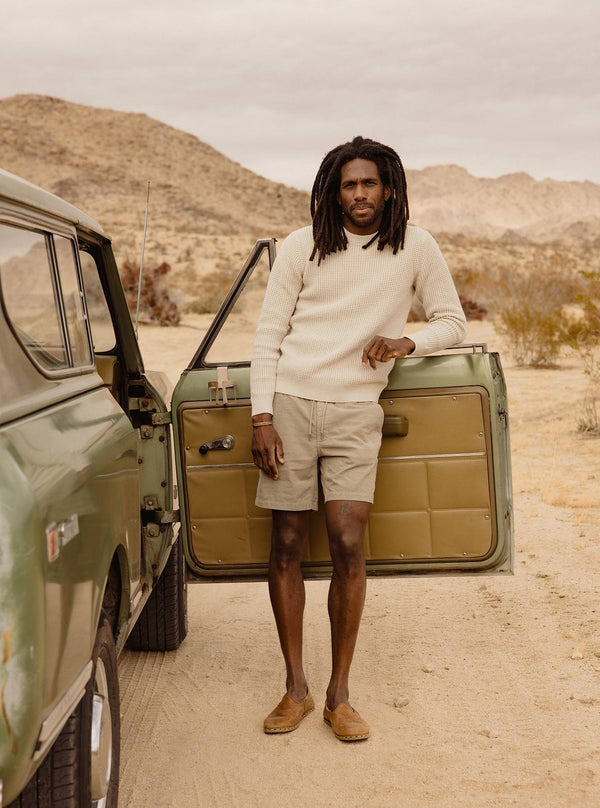 Model standing by the open door of a vintage car, wearing The Ranger Sweater and Après Shorts