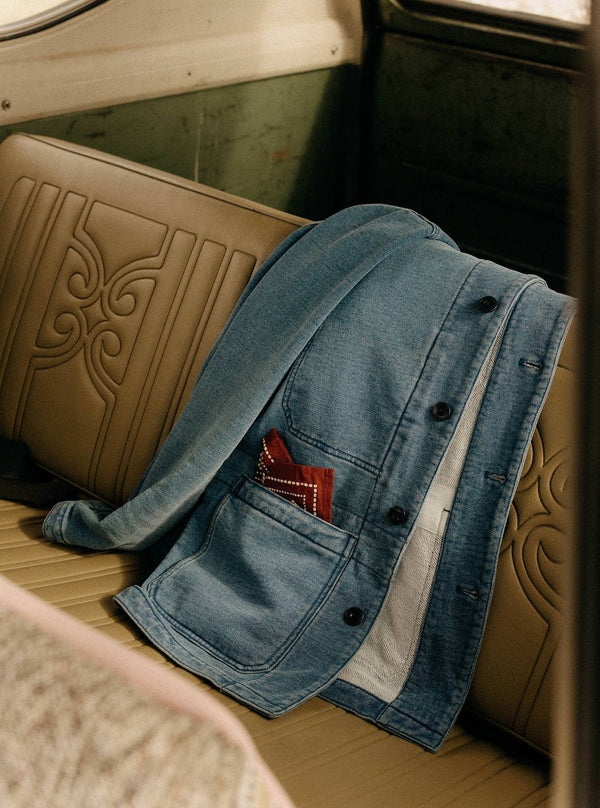 The Primer Jacket in Washed Indigo Terry draped over the leather seats of a vintage jeep