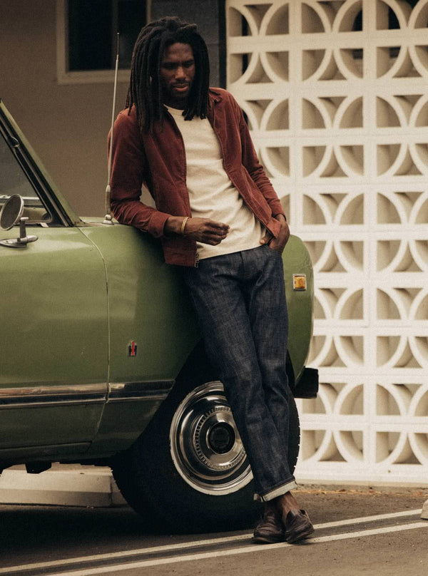 Model leaning against a vintage jeep, wearing the Piston Jacket