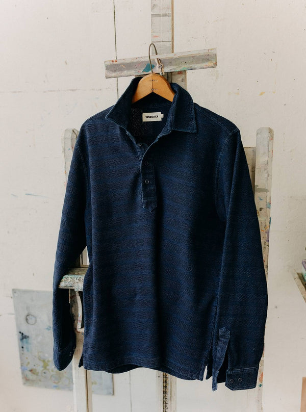 The Long Sleeve Knit Polo in Indigo Stripe hanging on an easel