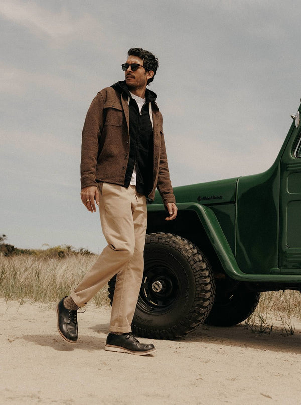 Model walking next to a jeep, wearing The Ledge Shirt and Apres Zip Hoodie