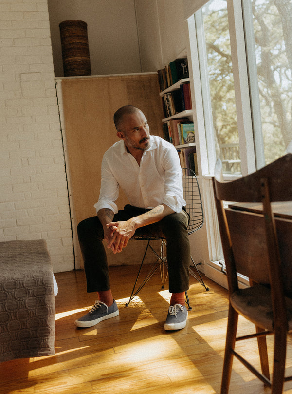 Model sitting on a chair, wearing The Hyde Shirt and Stevens Trouser